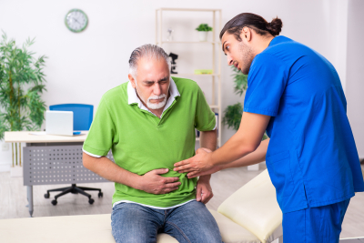 health worker assisting senior patient suffering from stomach pain