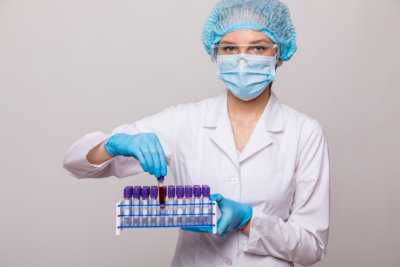 Close up female doctor hands with blood testing tube isolated on gray background