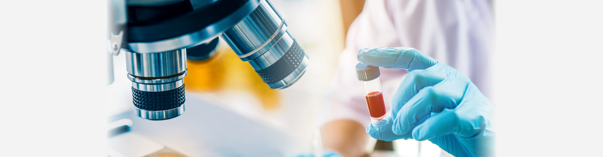lab technician assistant analyzing a blood sample in test tube at laboratory with microscope. Medical, pharmaceutical and scientific research and development concept.